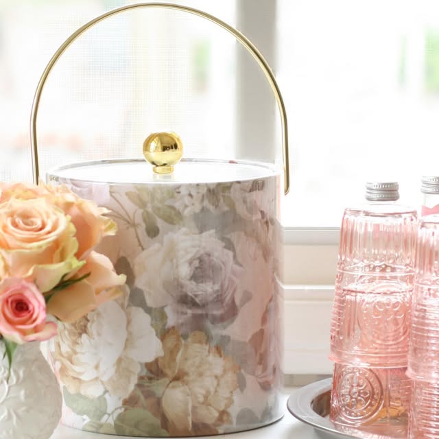 Floral ice bucket beside pink glassware and roses